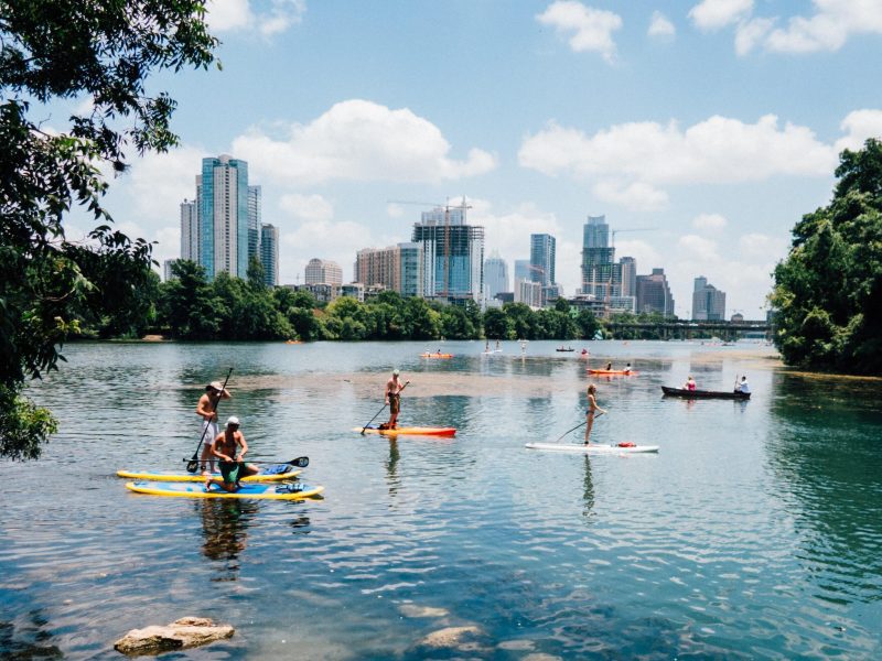 Group of paddle boarders on the water with the city skyline behind.