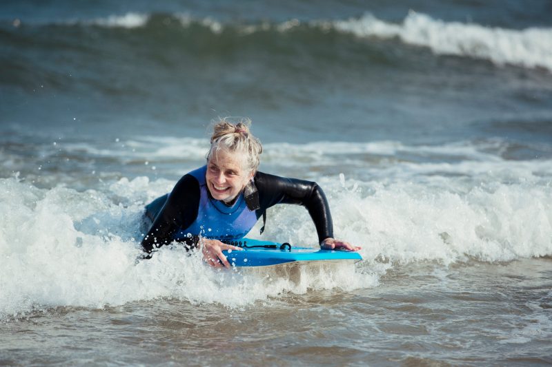 Mature Woman Rides on Shore on Boogie Board