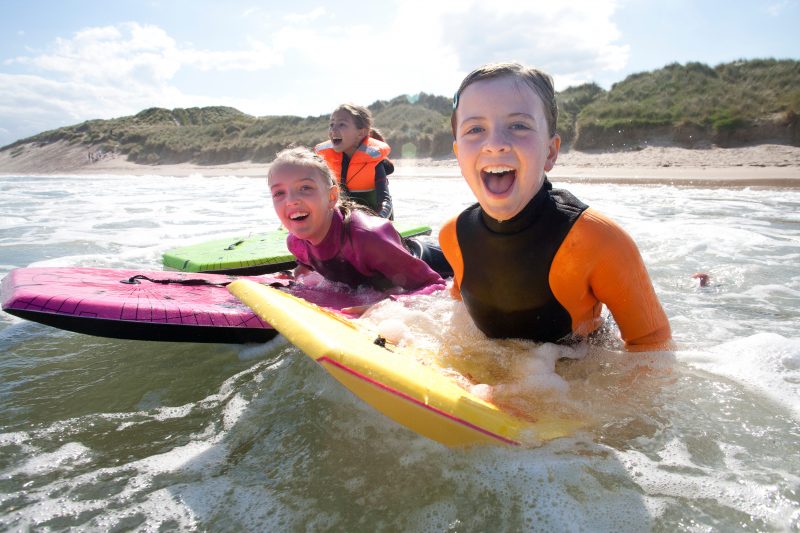 three young girls having a good time boogie boarding in the sea.