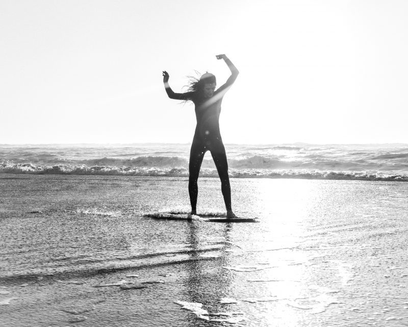 Woman Skimboarding on Beach