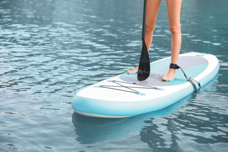 Young lady standing up on top of their paddle board.