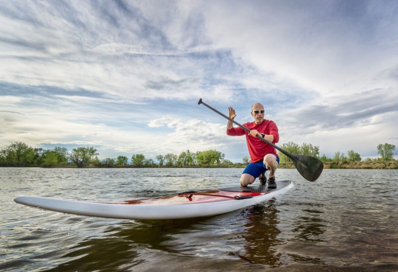 Senior male getting up on his feet on a paddle board.